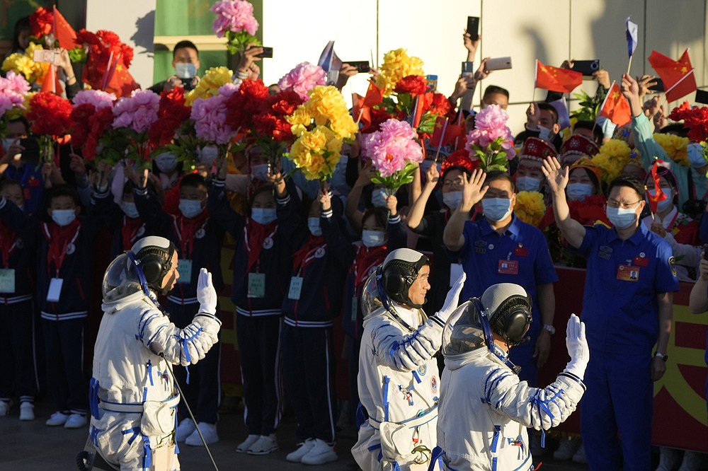 Chinese astronauts wave as they prepare to board for liftoff at the Jiuquan Satellite Launch Center in Jiuquan in northwestern China, Thursday, June 17, 2021. China plans on Thursday to launch three astronauts onboard the Shenzhou-12 spaceship who will be the first crew members to live on China's new orbiting space station Tianhe, or Heavenly Harmony. (AP Photo/Ng Han Guan)