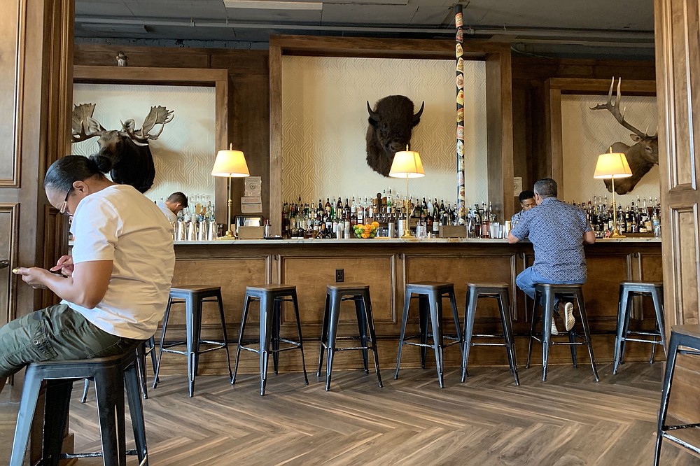 Stuffed moose, bison and deer heads decorate the wall behind the bar at Cannibal & Craft. (Arkansas Democrat-Gazette/Eric E. Harrison)
