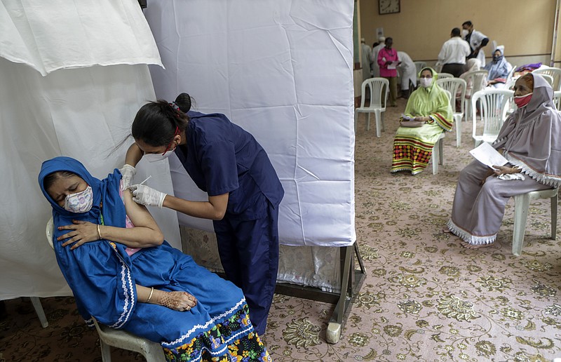 In this May 31 file photo, a woman gets inoculated against COVID-19 as others wait their turn at a vaccination center in Mumbai, India. Starting June 21, every Indian adult can get a COVID-19 vaccine dose for free that was purchased by the federal government. The policy reversal announced last week ends a complex system of buying vaccines that worsened inequities in accessing vaccines. India is a key global supplier of vaccines and its missteps have left millions of people waiting unprotected. The policy change is likely to address inequality but questions remain and shortages will continue. - AP Photo/Rajanish kakade