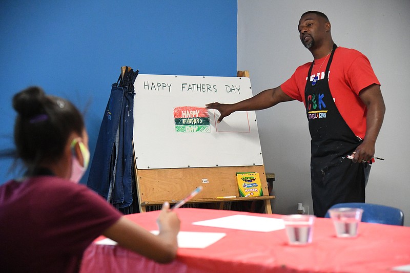 Malia Jeffrey participates in a Cutwell 4 Kids class on Saturday led by C4K founder Anthony Tidwell, right. Tidwell led the students in a Father’s Day themed painting project at the C4K Studio. Since the class fell on Juneteenth, the newly designated federal holiday’s colors of red, black and green were used in the project. - Photo by Tanner Newton of The Sentinel-Record