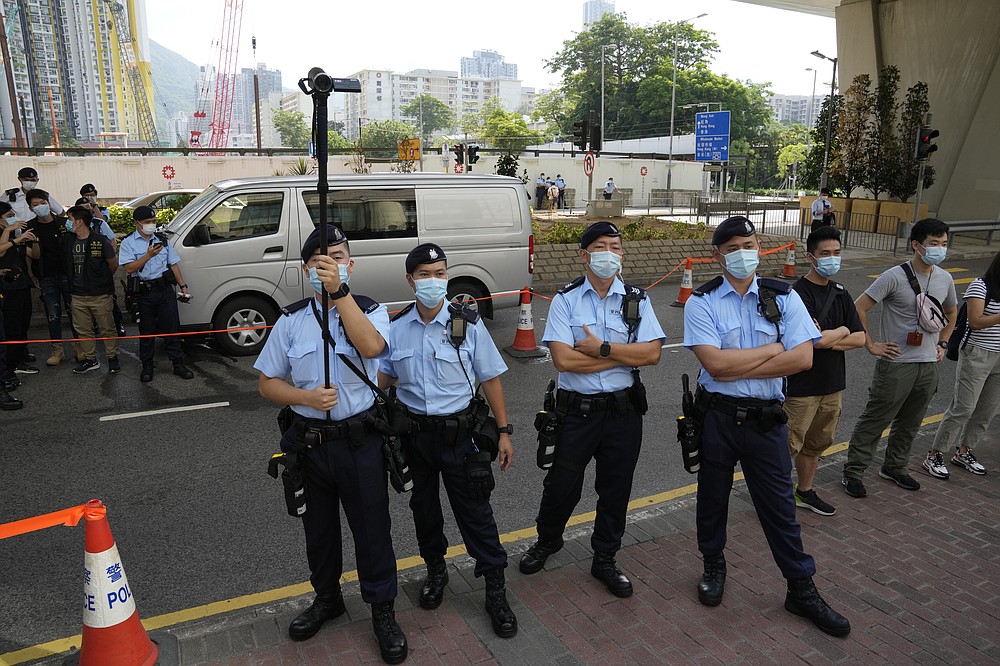 Police officers stand guard outside a court in Hong Kong, Saturday, June 19, 2021. The top editor of the Hong Kong's pro-democracy newspaper and the head of its parent company were brought to a courthouse Saturday for their first hearing since their arrest under the city's national security law. (AP Photo/Kin Cheung)