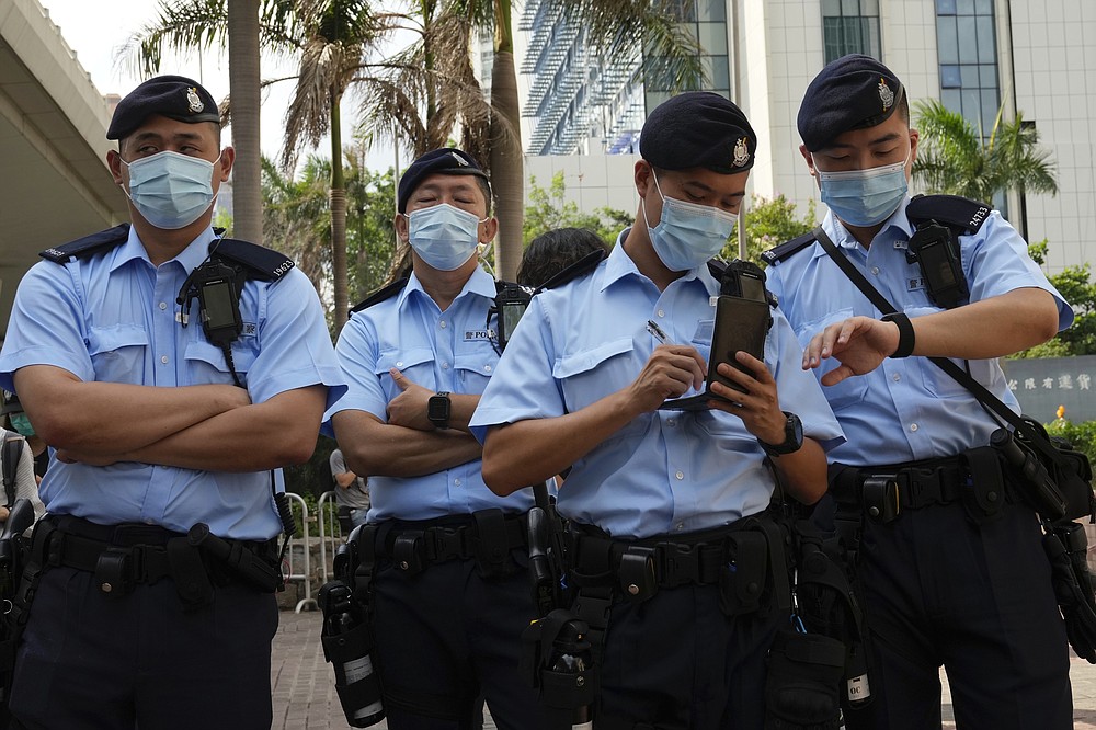 Police officers stand guard outside a court in Hong Kong, Saturday, June 19, 2021. The top editor of the Hong Kong's pro-democracy newspaper and the head of its parent company were brought to a courthouse Saturday for their first hearing since their arrest under the city's national security law. (AP Photo/Kin Cheung)