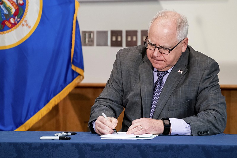 FILE - In this July 23, 2020, file photo, Gov. Tim Walz signed into law a sweeping package of police accountability measures in St. Paul, Minn., making Minnesota the latest state to adopt changes to law enforcement, including a ban on neck restraints, in the wake of George Floyd's death. The bill, passed by the Legislature earlier this week, also bans chokeholds and fear-based or "warrior-style" training, which critics say promotes excessive force. (Glen Stubbe/Star Tribune via AP, File)