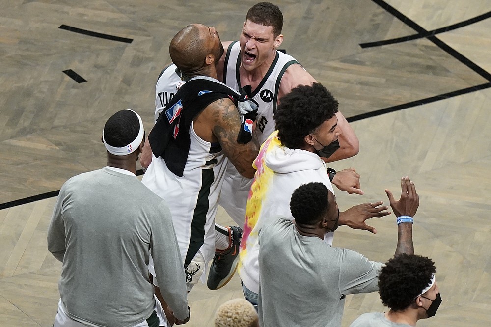 Milwaukee Bucks' Brook Lopez, right, celebrates with P.J. Tucker, left, and other teammates during overtime of Game 7 of a second-round NBA basketball playoff series Saturday, June 19, 2021, in New York. (AP Photo/Frank Franklin II)