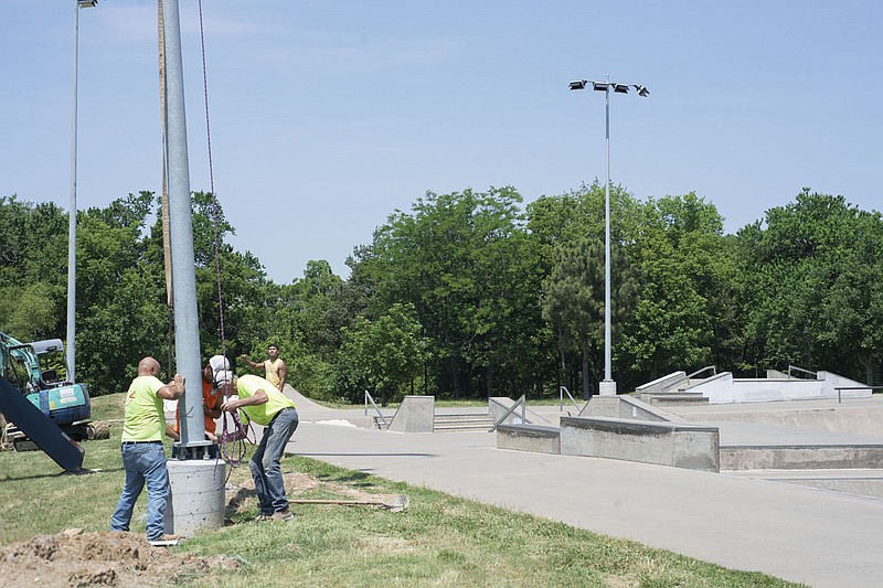 A crew installs lights Thursday June 17, 2021 at the Walker Park Skate Park in Fayetteville. The skate park opened in 2003 and skateboarders have been asking for lights ever since. Total budget for the lighting project was $98,000 coming out of the city√¢‚Ç¨‚Ñ¢s capital budget for parks. Users can turn the lights on with a button and the lights will automatically turn off when Walker Park closes at 11 P.M. Visit nwaonline.com/2100623Daily/ and nwadg.com/photo. (NWA Democrat-Gazette/J.T. Wampler)