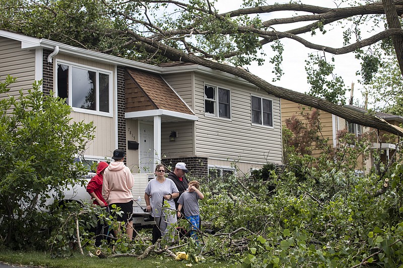 A family stands outside their home on Janes Avenue near Evergreen Lane in Woodridge, Ill., after a tornado ripped through the western suburbs overnight, Monday, June 21, 2021. (Ashlee Rezin Garcia/Chicago Sun-Times via AP