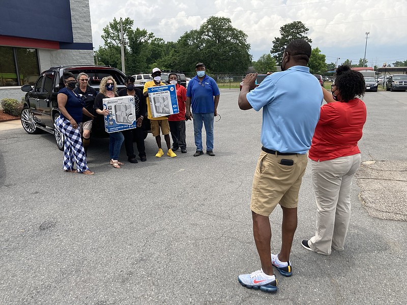 Standing in the foreground are Dishawn Bell, (left) general manager of Car-Mart, and Kendra Boone, the sales manager, as they take pictures of their employees and representatives of Area Agency on Aging. (Pine Bluff Commercial/Byron Tate)