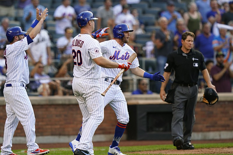 New York Mets' Jose Peraza, left, on-deck batter Pete Alonso (20) and Jeff McNeil, third from left, react at home plate after Peraza and McNeil scored on Dominic Smith's fifth-inning three-run double in the first baseball game of a doubleheader, Monday, June 21, 2021, in New York. Home plate umpire Ben May, right, looks on. (AP Photo/Kathy Willens)