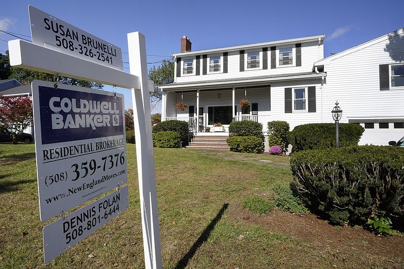 FILE - In this Oct. 6, 2020 file photo, a real estate brokerage sign stands in front of a house in Norwood, Mass. Sales of previously-occupied homes fell for the fourth straight month in May 2021, as soaring prices and a limited number of available properties discouraged many would-be buyers.  (AP Photo/Steven Senne, File)