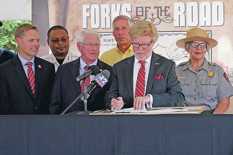 U.S. Rep. Michael Guest, R-Miss., and U.S. Sen. Roger Wicker, R-Miss., watch Natchez Mayor Dan Gibson sign the paperwork that donates the 2.86 acres of city-owned land where the Forks of the Road slave market existed, to the Natchez National Historical Park, a unit of the National Park Service (NPS), Friday, June 18, 2021, in Natchez, Miss. The land falls within the 18.5 acre legislatively authorized boundary of the Forks of the Road market where thousands of enslaved people were trafficked as chattel by slave traders from the Upper South and East Coast, and sold into the plantations of the Deep South. (AP Photo/Rogelio V. Solis)