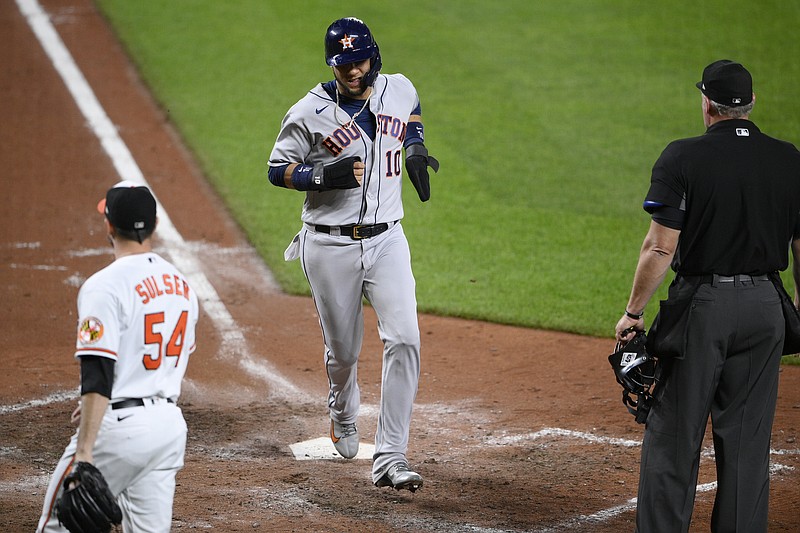 Houston Astros' Yuli Gurriel (10) scores a run on a sacrifice fly by Chas McCormick, not seen, during the eighth inning of a baseball game, Tuesday, June 22, 2021, in Baltimore. Baltimore Orioles relief pitcher Cole Sulser is at left. The Astros won 3-1. (AP Photo/Nick Wass)