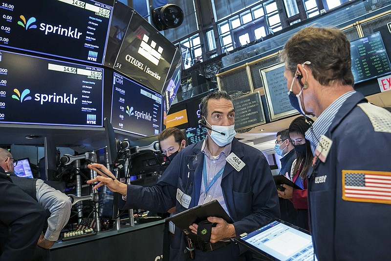 In this photo provided by the New York Stock Exchange, Gregory Rowe, center, talks with a fellow trader on the NYSE trading floor, Wednesday, June 23, 2021. A morning gain on Wall Street was fading away at midday Wednesday, leaving major indexes mixed. Investors are still trying to parse emerging signs of inflation and judge whether they will be transitory, as the Federal Reserve thinks they will. (Courtney Crow/New York Stock Exchange via AP)