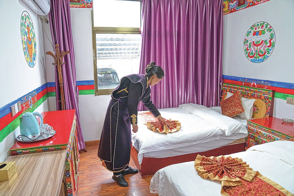 Eine Frau in ethnischer Kleidung passt am Freitag, den 4. Juni 2021, in ihrer touristischen Gastfamilie im Dorf Zhaxigang in der Nähe von Nyingchi in der westchinesischen Autonomen Region Tibet eine Bettdecke an. Der Tourismus in Tibet boomt, da mehr Chinesen aufgrund der Coronavirus-Pandemie im Land reisen Risiken für die fragile Umwelt und die historischen Stätten der Region.  (AP Foto/Mark Schiefebein)