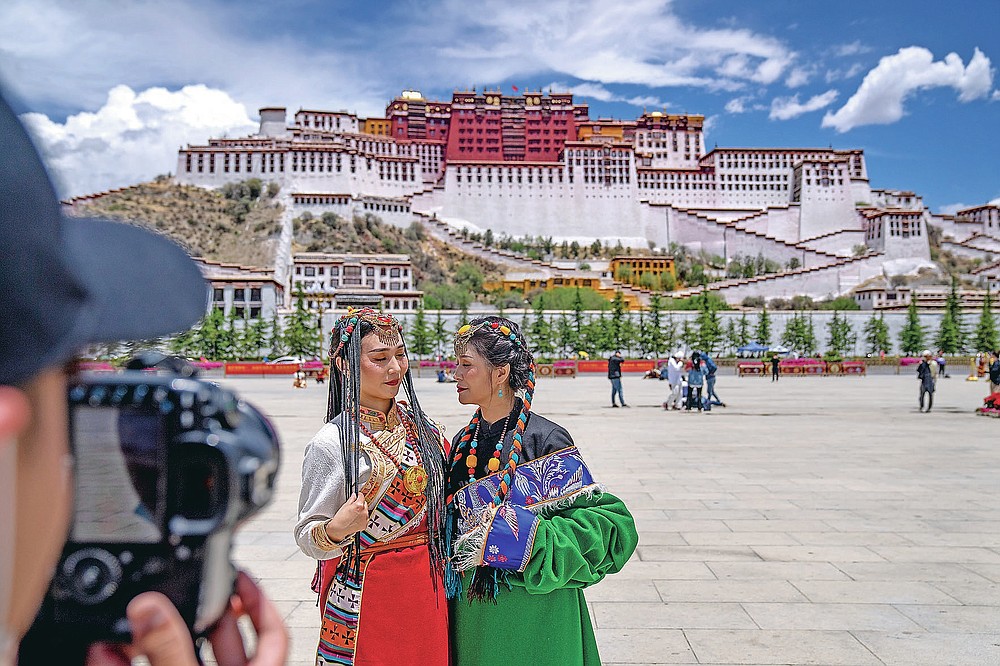 Chinesische Touristen in tibetischer Kleidung posieren für ein Foto auf einem Platz in der Nähe des Potala-Palastes in Lhasa in der westchinesischen Autonomen Region Tibet, Dienstag, 1. Juni 2021. Der Tourismus in Tibet boomt, da mehr Chinesen aufgrund der Coronavirus-Pandemie im Land reisen. Risiken für die fragile Umwelt und die historischen Stätten der Region darstellen.  (AP Foto/Mark Schiefebein)