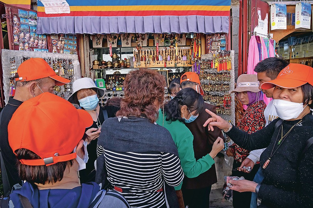 Mitglieder eines chinesischen Reisegruppenshops in einem Souvenirladen außerhalb des Jokhang-Tempels in Lhasa in der westchinesischen Autonomen Region Tibet, Dienstag, 1. Juni 2021. Der Tourismus in Tibet boomt, da mehr Chinesen aufgrund der Coronavirus-Pandemie im Land reisen. Risiken für die fragile Umwelt und die historischen Stätten der Region darstellen.  (AP Foto/Mark Schiefebein)