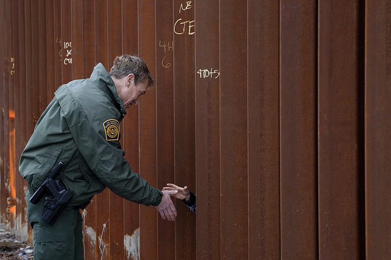 FILE - In this Jan 15, 2019, file photo, Rodney Scott, then-U.S. Border Patrol's San Diego sector chief shakes hands through a section of newly-replaced border wall in San Diego. The chief of the Border Patrol said Wednesday, June 23, 2021, he was leaving his job after less than two years in a position that lies in the crosshairs of polarizing political debate. Rodney Scott wrote to agents that he will be reassigned. (AP Photo/Gregory Bull, File)