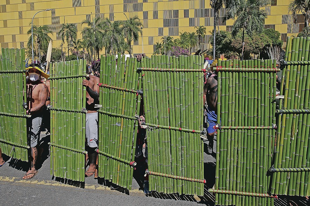 Indigenous with bamboo shields line up outside Congress in Brasilia, Brazil, Tuesday, June 22, 2021. Indigenous are camping in the capital to oppose a proposed bill they say would limit recognition of reservation lands. (AP Photo/Eraldo Peres)