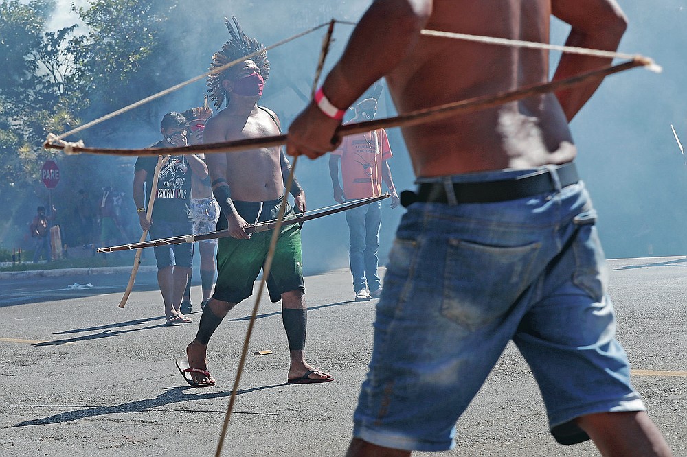 Indigenous armed with bows and arrows clash with police during a protest opposing a proposed bill the Indigenous protesters say would limit recognition of reservation land, outside Congress in Brasilia, Brazil, Tuesday, June 22, 2021. (AP Photo/Eraldo Peres)