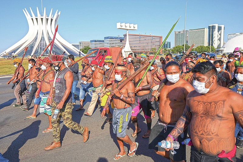 Indigenous march past the Cathedral in Brasilia, Brazil, Wednesday, June 23, 2021. Indigenous activists have traveled to the capital to demand government action to halt illegal mining and logging on their land and oppose a proposed bill they say would limit recognition of tribal lands. (AP Photo/Ricardo Mazalan)