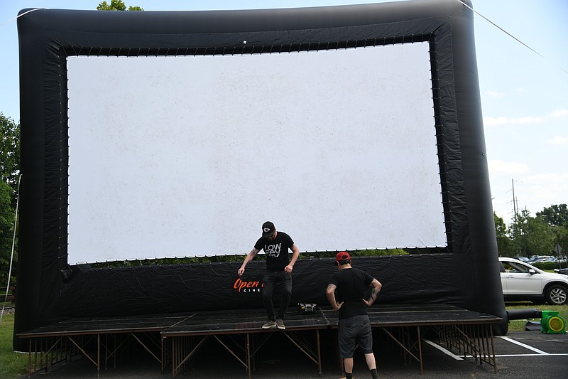Members of Low Key Arts help set up an inflatable movie screen for a Hot Springs Documentary Film Festival screening at the Hot Springs Farmers & Artisans Market. - Photo by Tanner Newton of The Sentinel-Record