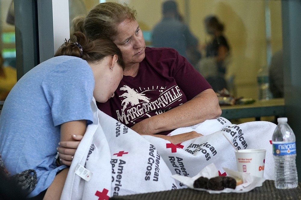 Jennifer Carr, right, sits with her daughter as they wait for news at a family reunification center, after a wing of a 12-story beachfront condo building collapsed, Thursday, June 24, 2021, in the Surfside area of Miami. Carr and her family were evacuated from a nearby building. (AP Photo/Lynne Sladky)