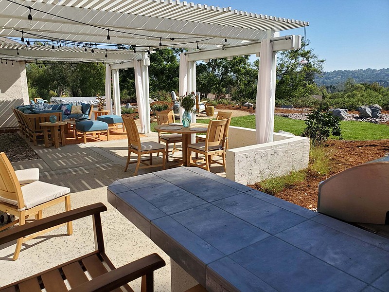 This image provided by John Beaudry shows a yard designed by Nikki Klugh, with an outdoor table that can be used as a desk and outdoor curtain panels to provide privacy and a good Zoom background for work calls. (John Beaudry via AP)