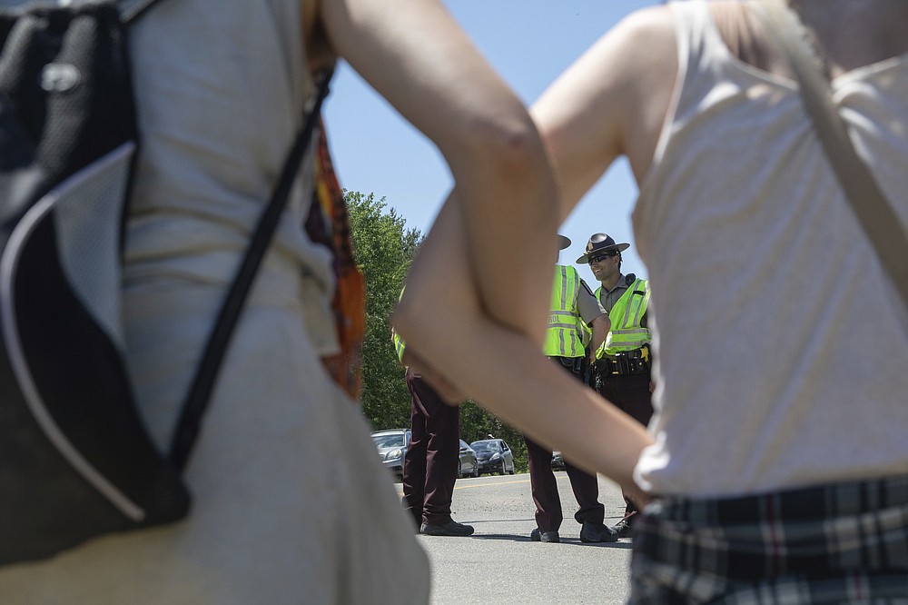 Activists lock arms as they occupy an Enbridge Line 3 pump station near Park Rapids, Minn., on Monday, June 7, 2021, as State Troopers, in background, direct traffic on Highway 71. (Evan Frost/Minnesota Public Radio via AP)