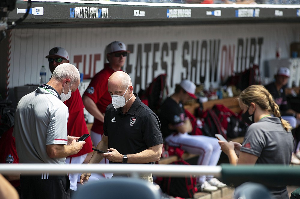 North Carolina State personnel chat in the dugout during a delay due to COVID-19 safety protocols before their baseball game against Vanderbilt in the College World Series Friday, June 25, 2021, at TD Ameritrade Park in Omaha, Neb. (AP Photo/Rebecca S. Gratz)