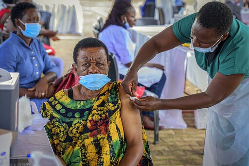 FILE - In this Monday, May 31, 2021 file photo, a woman receives a coronavirus vaccination at the Kololo airstrip in Kampala, Uganda. Virus cases are surging in Uganda, making scarce hospital beds even more expensive, and concern is growing over the alleged exploitation of patients by private hospitals accused of demanding payment up front and hiking fees. (AP Photo/Nicholas Bamulanzeki, File)