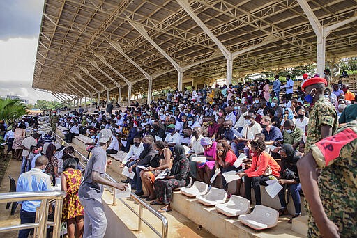 FILE - In this Monday, May 31, 2021 file photo, people wait in the stands to receive coronavirus vaccinations at the Kololo airstrip in Kampala, Uganda. Virus cases are surging in Uganda, making scarce hospital beds even more expensive, and concern is growing over the alleged exploitation of patients by private hospitals accused of demanding payment up front and hiking fees. (AP Photo/Nicholas Bamulanzeki, File)