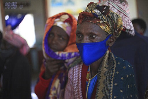 FILE - In this Tuesday, April 27, 2021 file photo, a woman waits for the AstraZeneca coronavirus vaccine at the Butanda Health Center III in Western Uganda. Virus cases are surging in Uganda, making scarce hospital beds even more expensive, and concern is growing over the alleged exploitation of patients by private hospitals accused of demanding payment up front and hiking fees. (AP Photo/Patrick Onen, File)