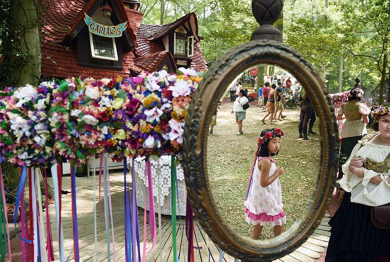 Xinyi Xie is reflected in a mirror as she walks by a booth selling garlands at the Maryland Renaissance Festival in 2015. (The Washington Post/Matt McClain)