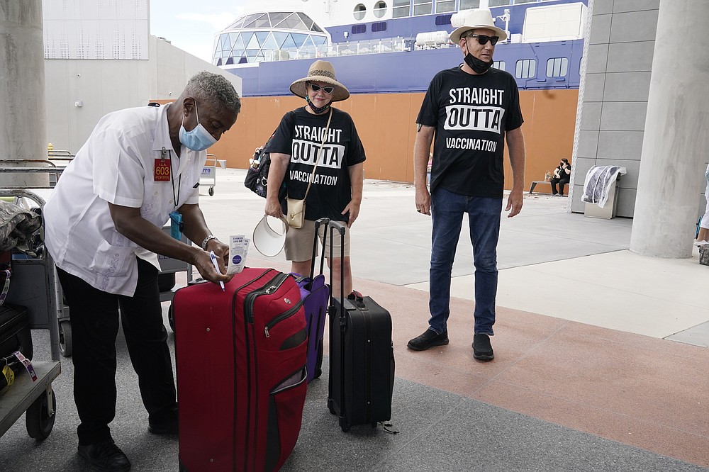Porter Johnny Jones Jr. tags the luggage of Celebrity Cruise passengers James and Cynthia Mitchell of Kansas, Saturday, June 26, 2021, in Fort Lauderdale, Fla. Celebrity Edge is the first cruise ship to leave a U.S. port since the coronavirus pandemic brought the industry to a 15-month standstill. The cruise ship has 40 percent capacity, and with virtually all passengers vaccinated against COVID-19. (AP Photo/Marta Lavandier)