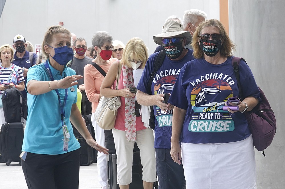 Orchid Klaric, left, assists Brenda and Kurt Duncan of Denver, with checking into their cruise, Saturday, June 26, 2021, in Fort Lauderdale, Fla. Celebrity Edge is the first cruise ship to leave a U.S. port since the coronavirus pandemic brought the industry to a 15-month standstill. The seven-night cruise will have 40 percent capacity and with virtually all passengers vaccinated against COVID-19. (AP Photo/Marta Lavandier)