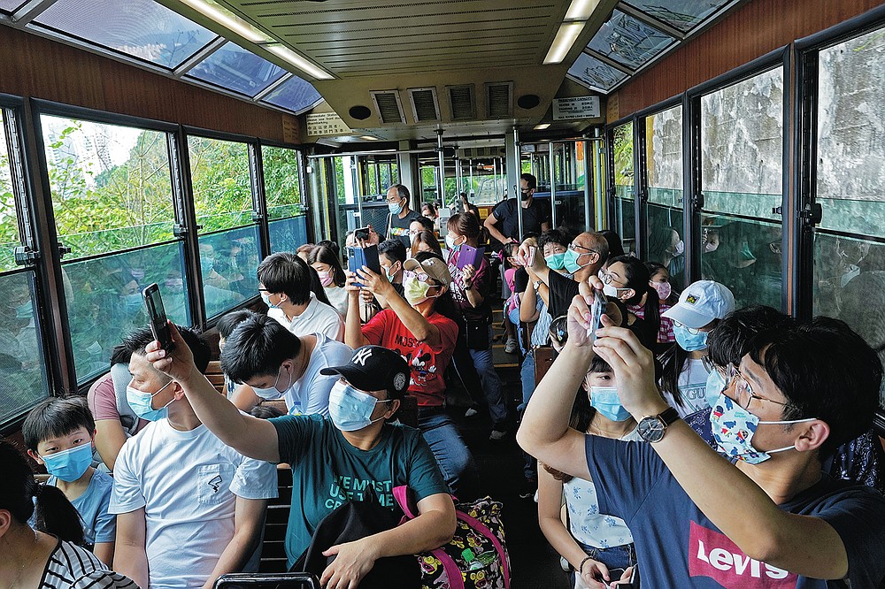 Passengers take photos of a Peak Tram on a tram trip in Hong Kong on June 17, 2021. The Hong Kong Peak Tram is a staple in the memory of many residents and tourists, carrying passengers to Victoria Peak for a bird's eye view of the many skyscrapers.  (AP Photo / Vincent Yu)