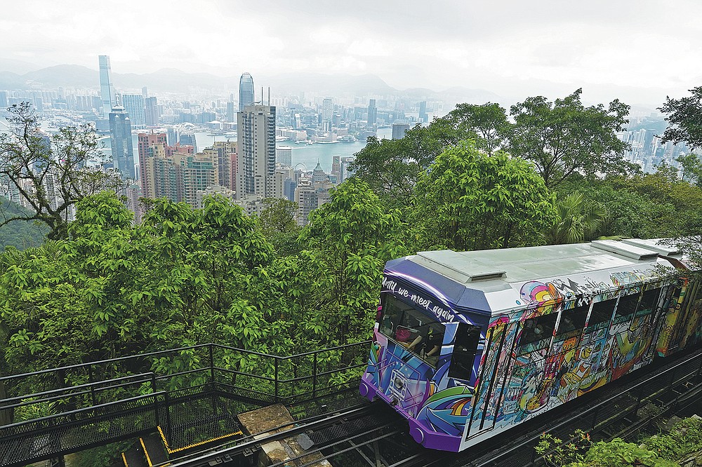 A Peak Tram passes a climb of Victoria Peak against the backdrop of Hong Kong on June 17, 2021. The Hong Kong Peak Tram is a staple in the memory of many residents and tourists, carrying passengers up to Victoria Peak for a view plunging over the many skyscrapers in the city. (AP Photo / Vincent Yu)
