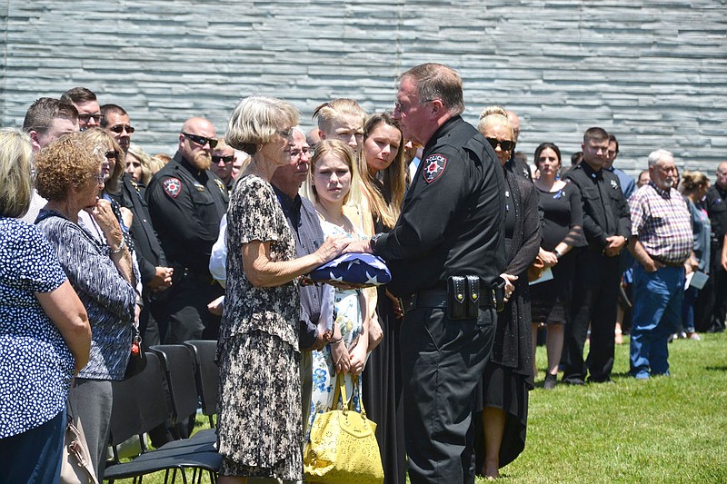 Dalene Hart, center left, received the flag that draped her son's casket from Pea Ridge Police Chief Lynn Hahn, during the outside memorial that followed the funeral service for slain Pea Ridge Police Officer Kevin Apple Friday, July 2, at Cross Church.