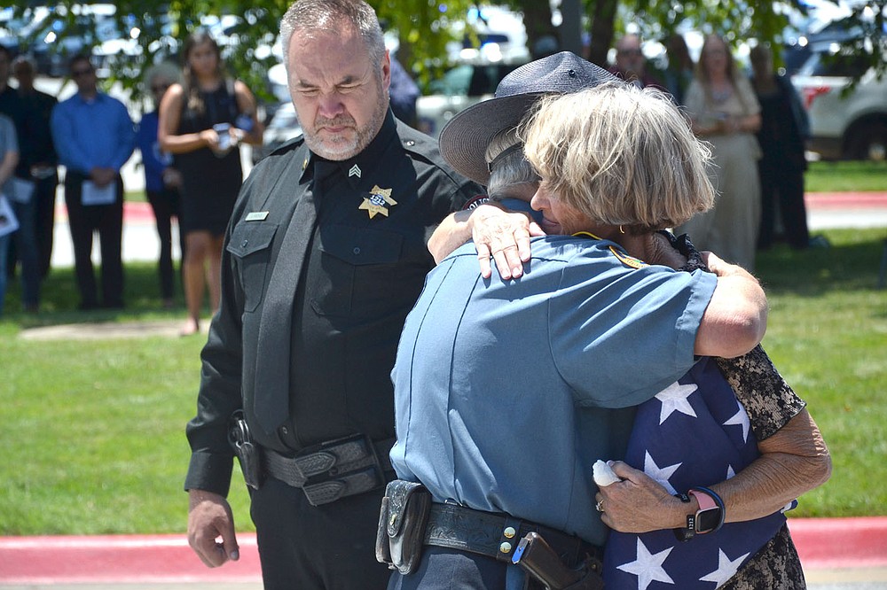 Dalene Hart, mother of slain Pea Ridge Police Officer Kevin Apple, was being escorted to her vehicle by Pea Ridge Police Sgt. John Hicks after the service for her son, when she stopped to hug Sammy Johnson, a deputy from Yell County, Friday, July 2, 2021, at Cross Church, Pinnacle Hills, Rogers. Johnson said he knew Apple and Hart.