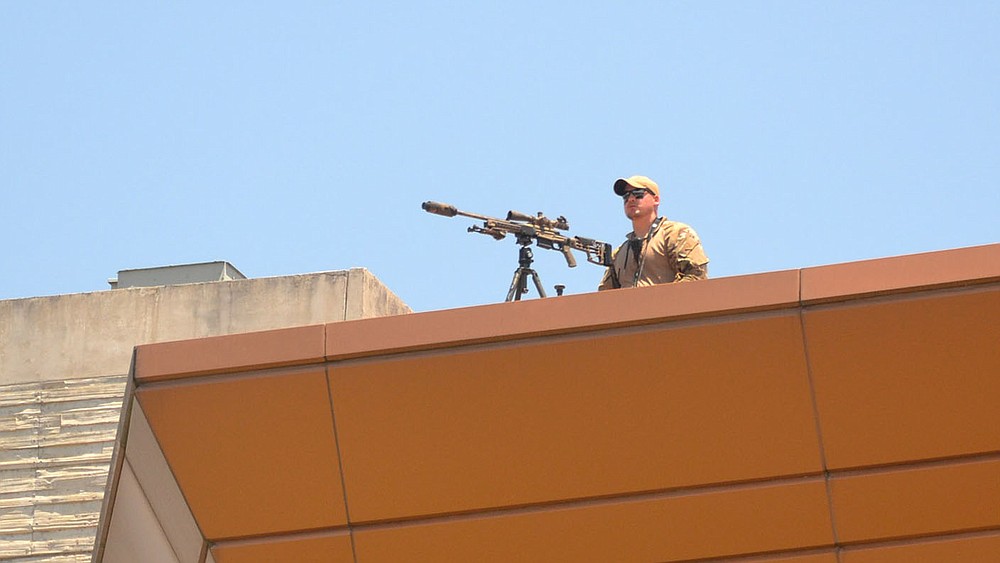 A Benton County Sheriff's deputy stands watch from the roof top during the outdoor memorial service following the funeral for Pea Ridge Police Officer Kevin Apple.