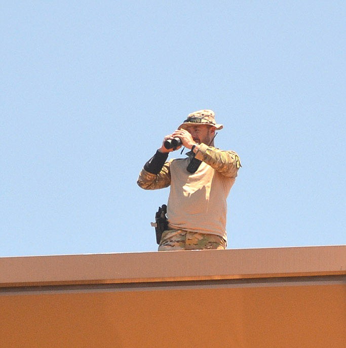 A Benton County Sheriff's deputy stands watch from the roof top during the outdoor memorial service following the funeral for Pea Ridge Police Officer Kevin Apple.