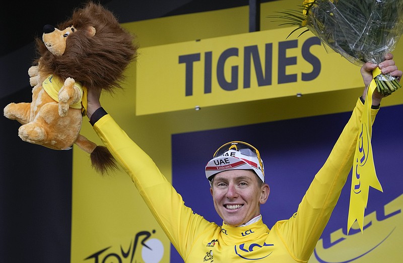 Slovenia's Tadej Pogacar, wearing the overall leader's yellow jersey, celebrates on the podium after the ninth stage of the Tour de France cycling race over 144.9 kilometers (90 miles) with start in Cluses and finish in Tignes, France, Sunday, July 4, 2021. (AP Photo/Christophe Ena)