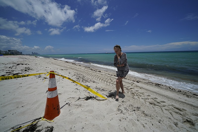 FILE - In this July 2, 2021, file photo, community resident Elizabeth Marts visits the beach near the Champlain Towers South condo building to pay her respects, one week after it partially collapsed with scores of residents inside in Surfside, Fla. (AP Photo/Gerald Herbert, File)