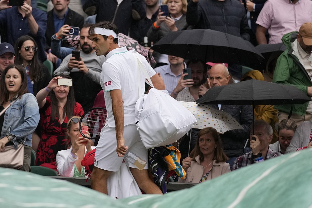 Le Suisse Roger Federer quitte le terrain en raison de la pluie qui a retardé le match lors du match de quatrième tour du simple messieurs contre l'Italien Lorenzo Sonego le septième jour des championnats de tennis de Wimbledon à Londres, le lundi 5 juillet 2021 (AP Photo / Kirsty Wigglesworth).