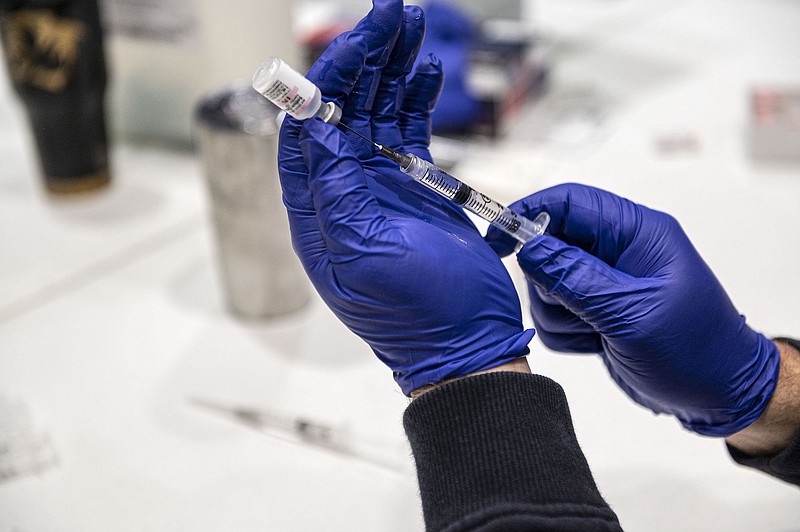 Tony Johnson a paramedic with the Bentonville Fire Department fills syringes with Pfizer Covid-19 vaccines Thursday March 19, 2021  along with other Bentonville Fire Fighters at Station No. 1 where the city was give out vaccinations.. (NWA Democrat-Gazette/Spencer Tirey)