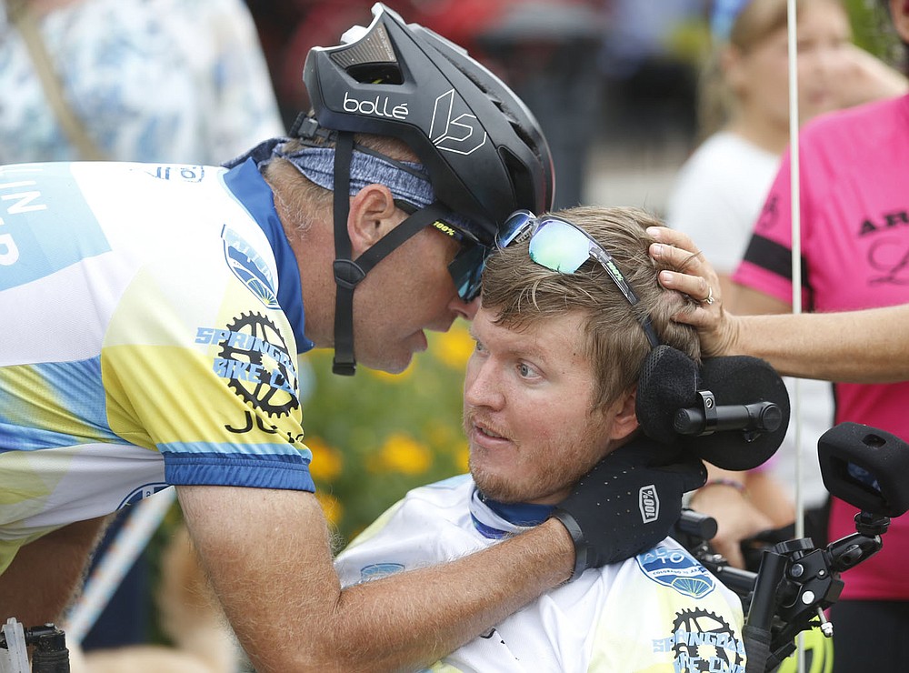 Josh Fohner is surrounded by teammates, well wishers and friends Thursday, July 1, 2021, after arriving at Shiloh Square in downtown Springdale. Fohner, the inspiration behind the All In For Josh Ride, was finishing up a 908 mile bicycle ride that started in Buena Vista, CO. to Springdale. The Springdale native was seriously injured in a biking accident in 2016 and suffered severe brain injuries. Check out nwaonline.com/210702Daily/ and nwadg.com/photos for a photo gallery.(NWA Democrat-Gazette/David Gottschalk)