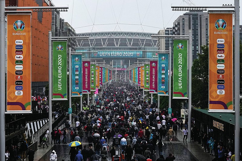 Supporters make their way to Wembley stadium in London, Tuesday, June 29, 2021 as they arrive for the Euro 2020 soccer championship round of 16 match between England and Germany. Arguably, no country has elevated sport's role in society quite as much as Britain so the absence of crowds for much of the coronavirus pandemic has been a constant reminder, if any were needed, of the cultural toll of COVID-19. The steady return of fans to sports over the past few weeks and the promise of packed-out stadiums very soon provide hope that life is returning to normal in the wake of the rapid rollout of coronavirus vaccines. (AP Photo/Matt Dunham)