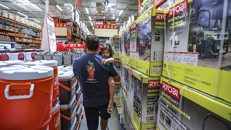 Frank Barakat carries his daughter Valentina, 2, through an shopping aisle dedicated for hurricane supplies as the Home Depot store prepares for possible effects of tropical storm Elsa in Miami on Saturday, July 3, 2021. Elsa fell back to tropical storm force as it brushed past Haiti and the Dominican Republic on Saturday and threatened to unleash flooding and landslides before taking aim at Cuba and Florida.  (Al Diaz/Miami Herald via AP)