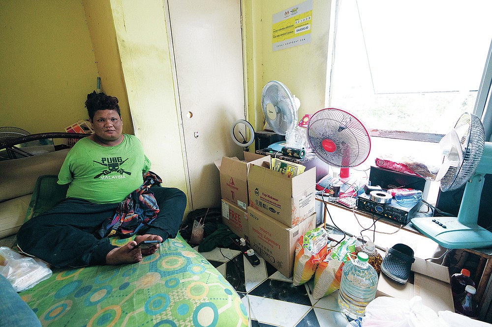Mohamad Nor Abdullah, born without arms, sits near donated goods, right, in his rented room in Kuala Lumpur, Malaysia on July 3, 2021. When Mohamad Nor put a white flag outside his window late at night, he didn’t expect the swift outpouring of support. By morning, dozens of strangers knocked on his door, offering food, cash and encouragement. (AP Photo/Vincent Thian)