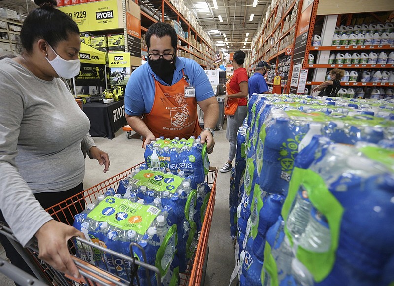Home Depot department supervisor, Arnaldo Gonzalez, loads water bottles into Elena Arvalo's shopping cart as shoppers prepare for possible effects of tropical storm Elsa in Miami on Saturday, July 3, 2021. Elsa fell back to tropical storm force as it brushed past Haiti and the Dominican Republic on Saturday and threatened to unleash flooding and landslides before taking aim at Cuba and Florida.  (Al Diaz/Miami Herald via AP)