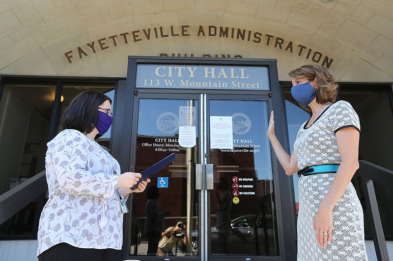 Kara Paxton (left), Fayetteville city clerk, administers the oath of office on July 24, 2020, to Dr. Marti Sharkey as the city's public health officer on the steps of City Hall in Fayetteville. The City Council on Tuesday voted to continue operation of the city's Board of Health. (File photo/NWA Democrat-Gazette/David Gottschalk)